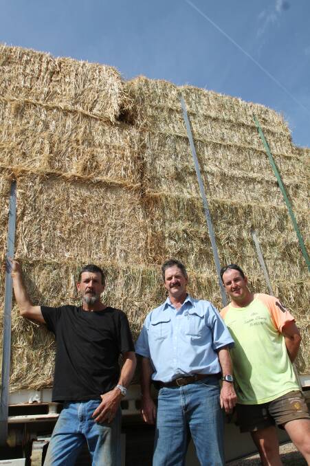 LOCKED AND LOADED: Stockinbingal's Paul Lukins, Bob Morton and Greg Morton loading the truck with 44 bales of hay before the hay run last Thursday. Picture: Rebecca Fist