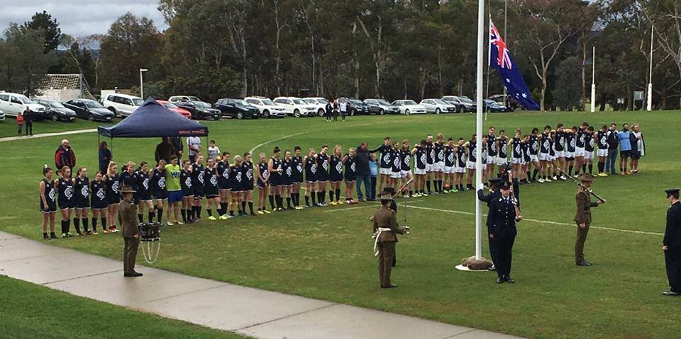 QUIET RESPECT: The Blues men and women pause for a moment's reflection during the Anzac Day commemorative round against the ADFA/RMC Rams. Picture: Cootamundra Blues Football Club.
