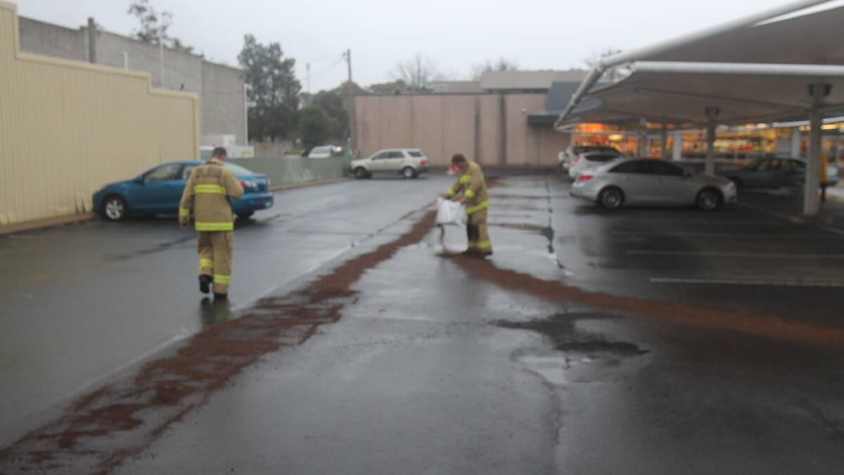 Firefighters apply sawdust to diesel leakage around Cootamundra Woolworths. Picture: Lachlan Grey. 