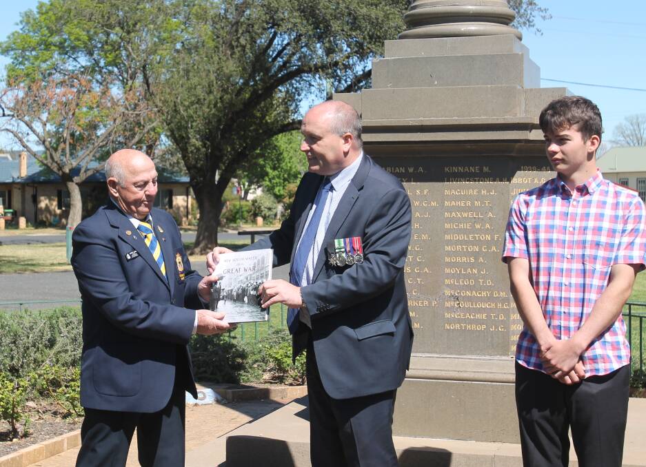 HONOUR: Cootamundra RSL Sub-branch chairman Garry James exchanges offerings with Minister for Veterans Affairs David Elliot as Cootamundra High's Oliver Litchfield looks on. Picture: Kathy Macglagan