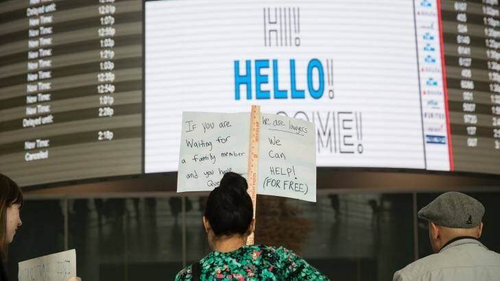 Volunteer lawyers stand with signs to greet arriving passengers in John F. Kennedy International Airport in New York,. Photo: New York Times