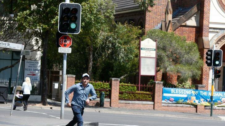 Sun Herald : Sydney. Story by, Eamonn Duff. How a Sydneysider can break the law 10 times a day without realising:
Nick Maxwell with his dog Byron,  acts out the offending laws. J walking within a cetain distance of a pedestrian crossing.   Photo: Peter Rae Friday 9 October 2015. Photo: Peter Rae