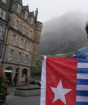 Benny Wenda flies the West Papuan flag in the shadow of Edinburgh Castle. Photo: Nick Miller