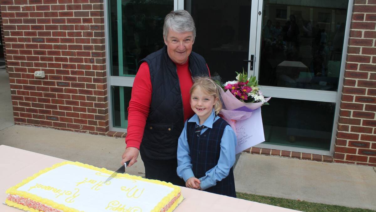 CAKE AND FLOWERS: Sacred Heart Central School last Friday farewelled Judy Hart, who served as canteen manager for 21 years. Judy is pictured here with Year One student Sarah Harris.