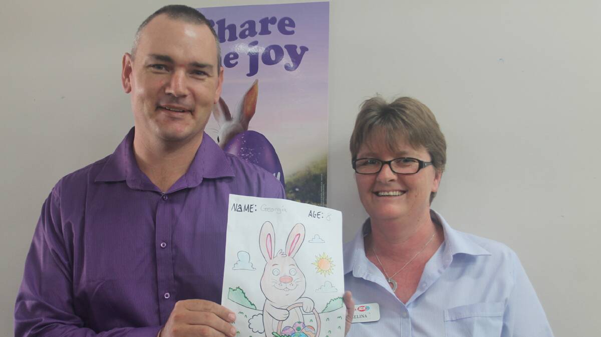 WINNING ENTRIES: Cootamundra Herald Managing Editor Heath Harrison and IGA’s Selina Loiterton are pictured with one of the winning entries in the Cootamundra IGA Easter colouring in competition. The talented winners were Georgie O’Mara and Benjamin Wilde. 
