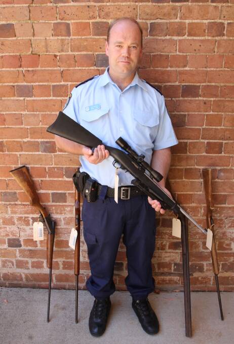FIREARMS FOUND: Detective Senior Constable Mark Lake holding five of the nine firearms that went missing last Friday from a Back Brawlin Road property.
