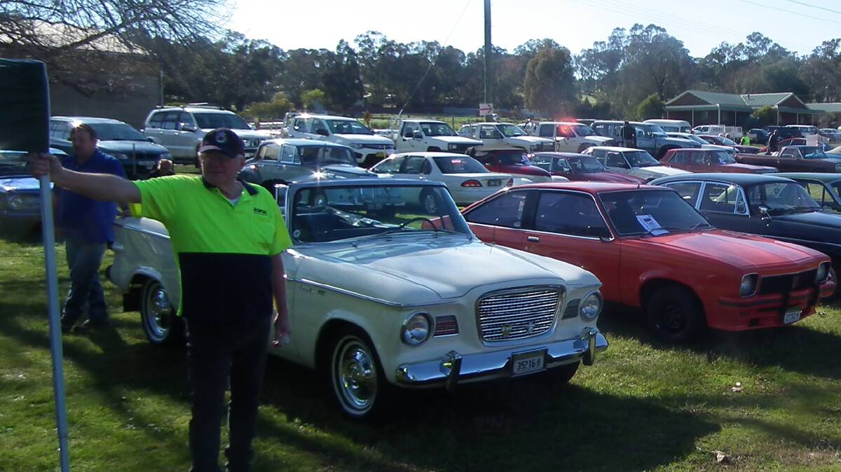 STANDING GUARD: Brian Morgan directs traffic at last year’s swap meet whilst keeping an eye on a Studebaker Lark convertible and SS Torana.