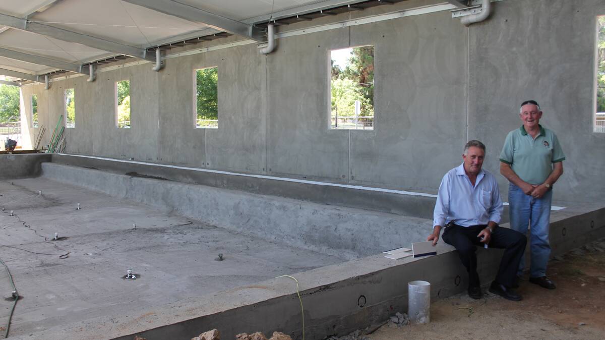 COMING ALONG WELL: Cootamundra deputy mayor Dennis Palmer (seated) and mayor Jim Slattery look over the construction of heated pool. Dennis is holding the tiles that will be used. Both agree it will be a great community facility once complete. 