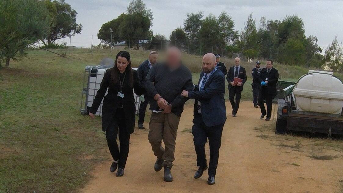 NSW Police leading the 61-year-old man who was arrested on Wednesday morning. Photo: NSW Police.