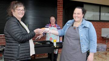 Jo Pavert enjoyed a Democracy sausage at the Cootamundra Public School after casting her vote in the Federal Election, the BBQ was manned by School principal Lucy Greene and school chaplain Sue Masters. Photo by Kelly Manwaring.