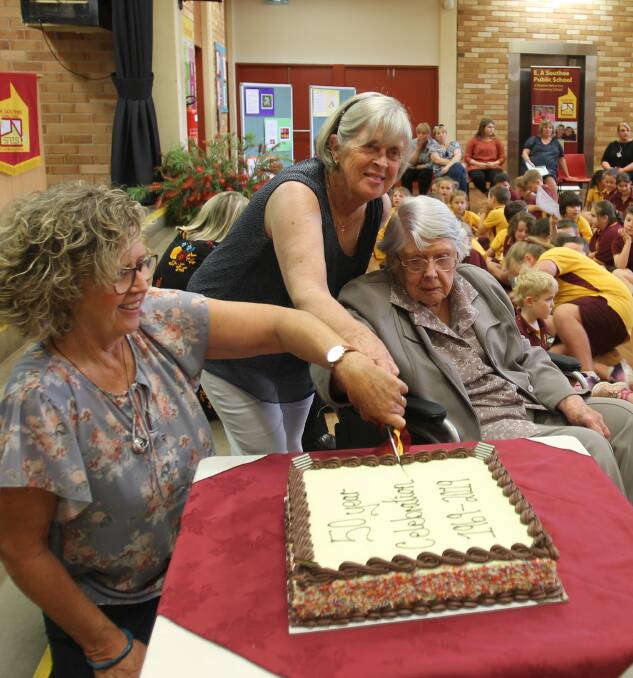 Bev Tucker and Judy Brady, granddaughters of E A Southee, with their mother Joyce Marshman, cutting the cake at the special assembly.
