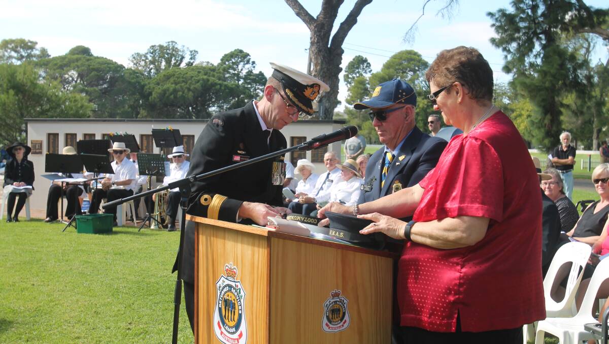 CONNECTION: Commodore Darron Kavanagh ties tally bands onto Navy caps, watched by Cootamundra RSL sub-branch secretary Jacqui Vincent and president Garry James.