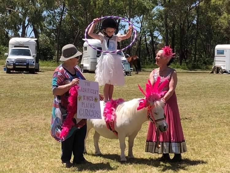 The Magnificent Kings Plains Circus, featuring Margaret Wilson standing on the back of wonder pony Pip, with grandmother Helena Donaldson (holding the sign) and Cazzie Hedge. 