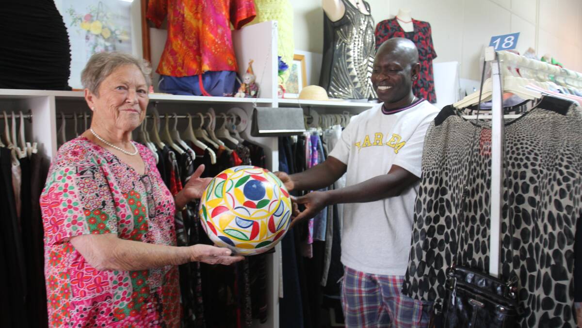 Red Cross Shop Voluntary Manager Helen Eccleston receives the calabash from Romeo Remi, in thanks for clothes now being worn in Nigeria.