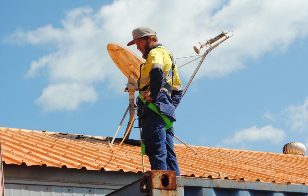 GROWING DEMAND: A technician installs a National Broadband Network roof-top antenna on the roof of a house. Picture: NBN