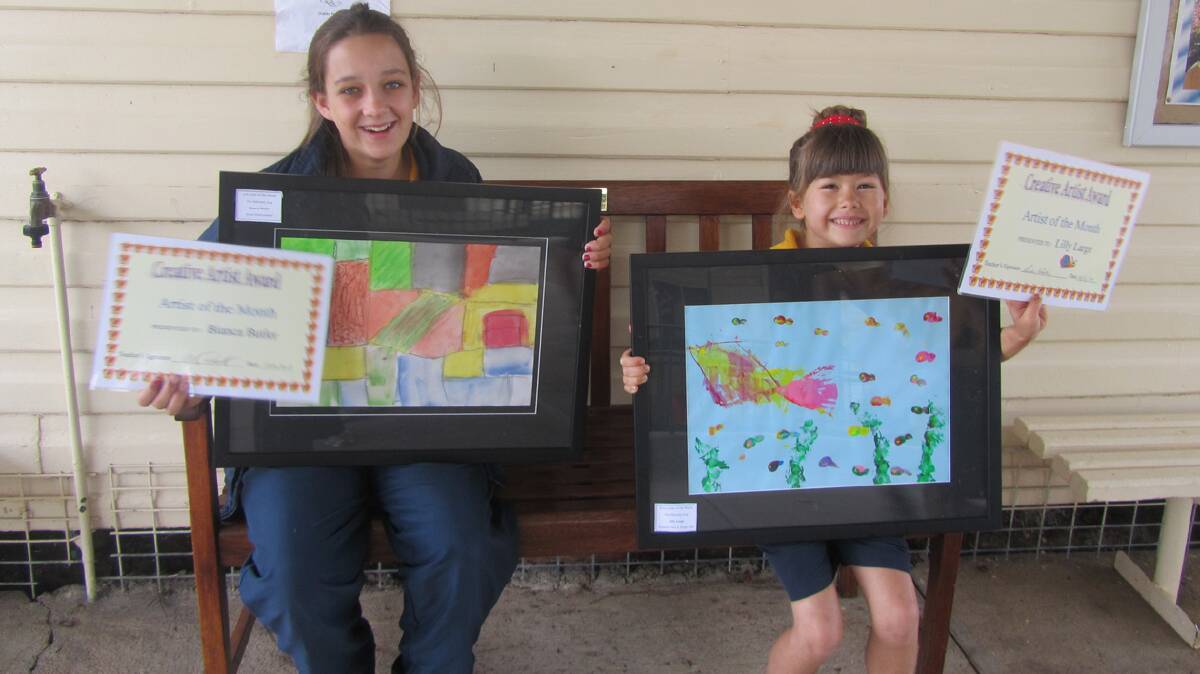  ARTISTS OF THE MONTH: Stockinbingal Public School student Lily Large is pictured with her ‘Fantastic Fan and Finger Fish’ work of art (right) while Bianca Butler shows her ‘Aerial Environment’ work. Both girls were named Artists of the Month. 
