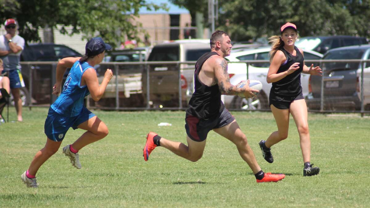 BREAKING THE LINE: Chris Maher (centre) makes a break for the Family Hotel Villains, with Mikayla Large in support during the 2016 touch carnival. Photo: Harrison Vesey
