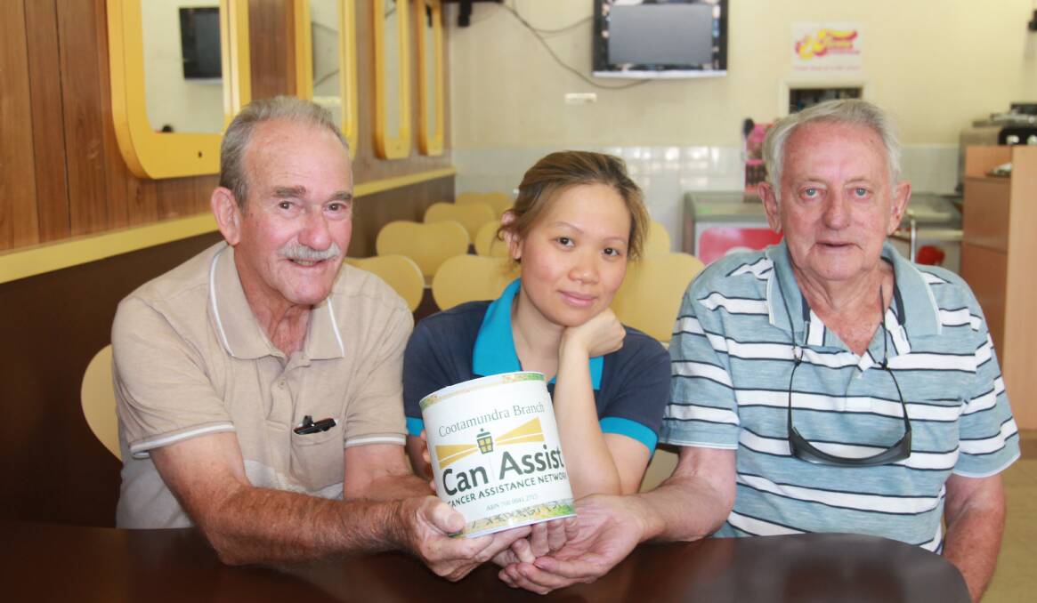 RATTLING TIN: Can Assist members Clarrie Power and Neil Murray collect a donation tin from Popular Cafe owner Carmen Chau. Photo: Declan Rurenga